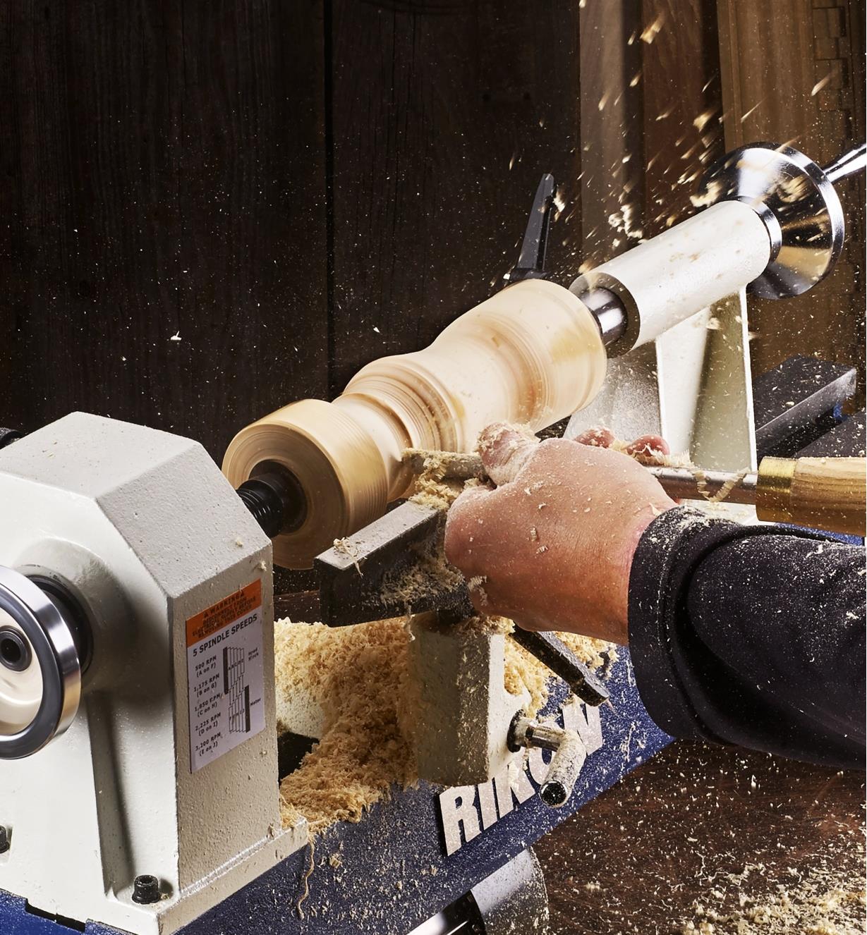 A woodworker turns a peppermill on a Rikon model 70-105 mini lathe