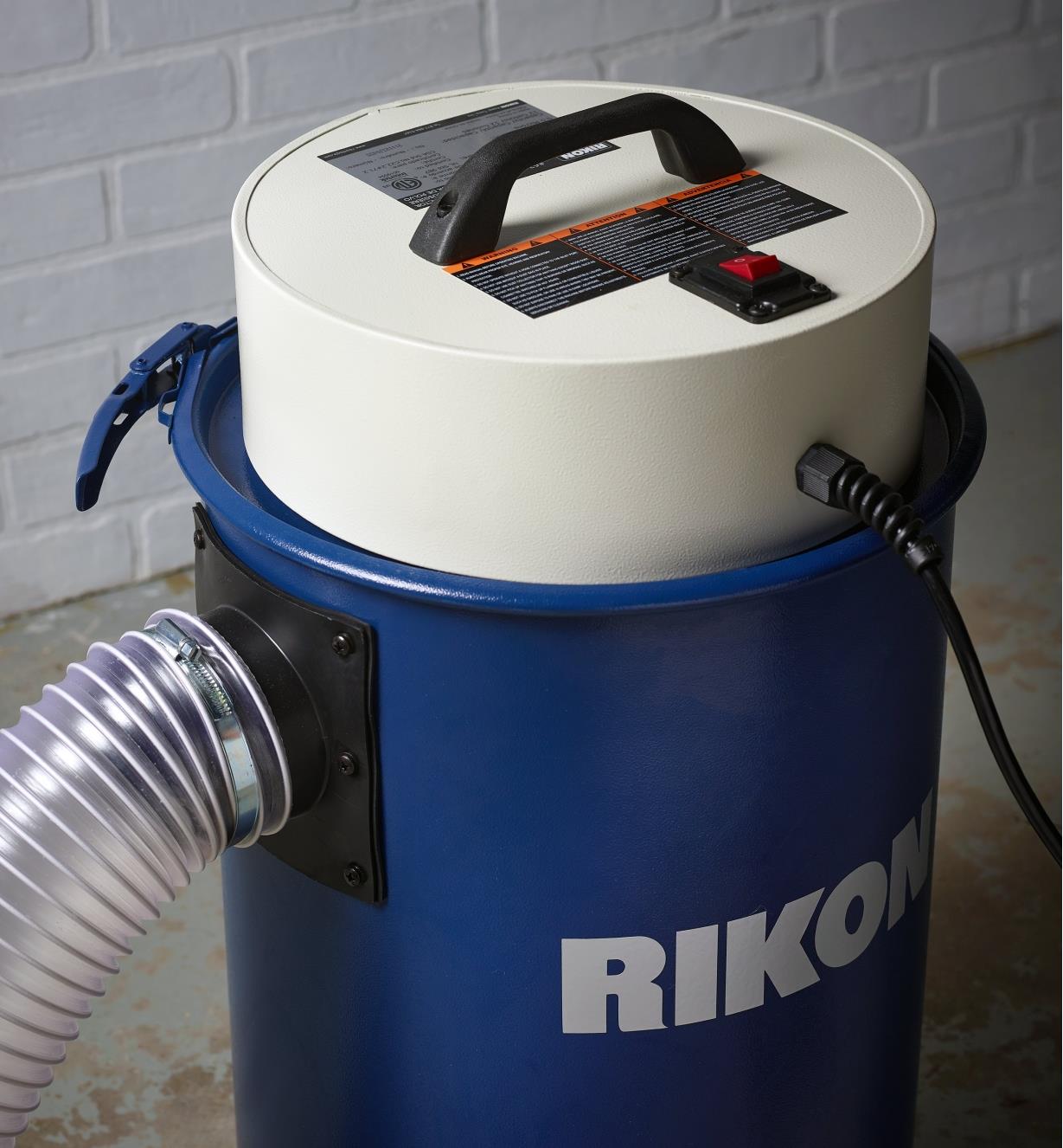 A 4” diameter hose connected to a Rikon 12 gallon dust extractor with an included hose clamp