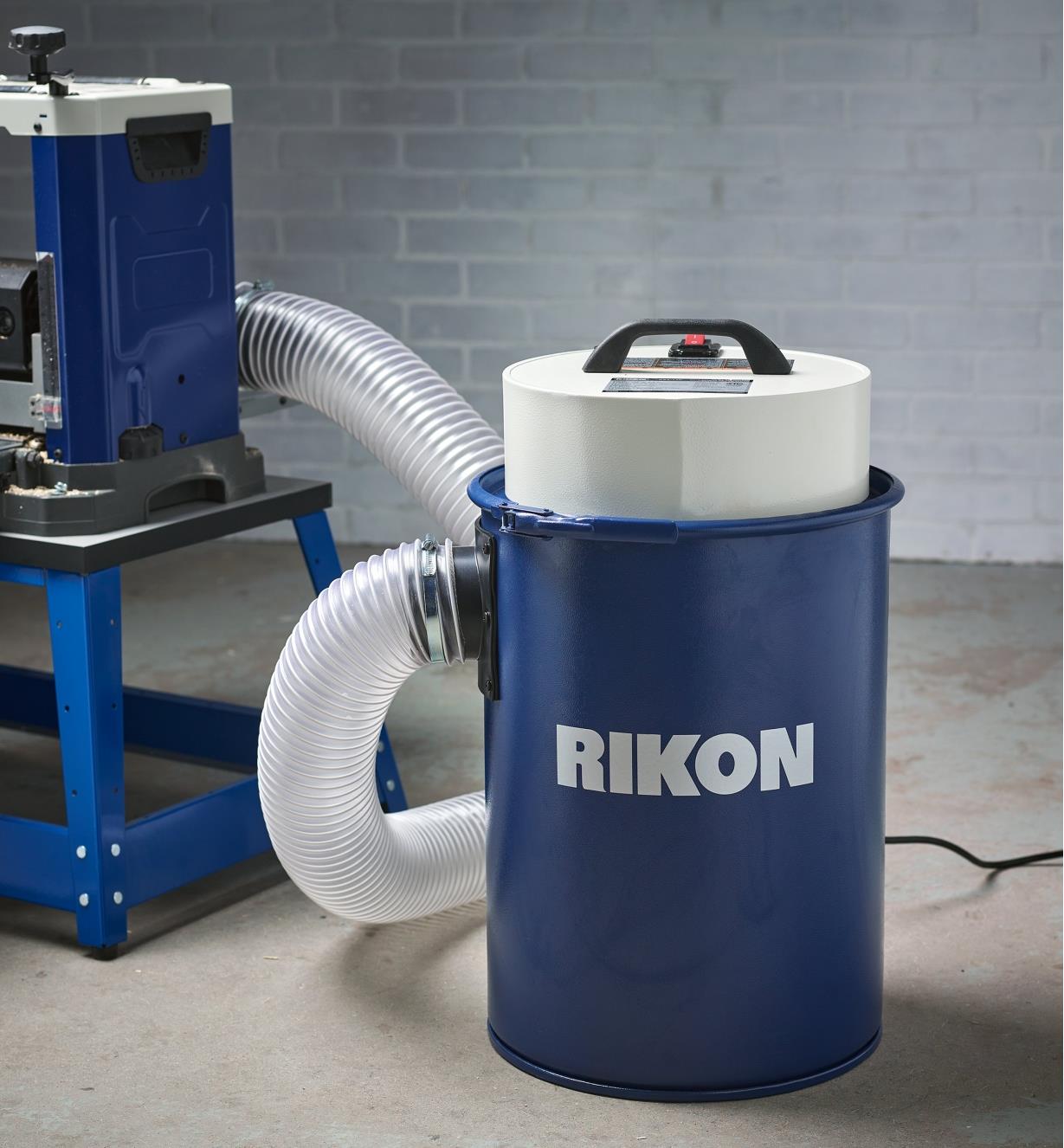 A Rikon 12 gallon dust extractor connected with a 4” diameter hose to a Rikon helical planer