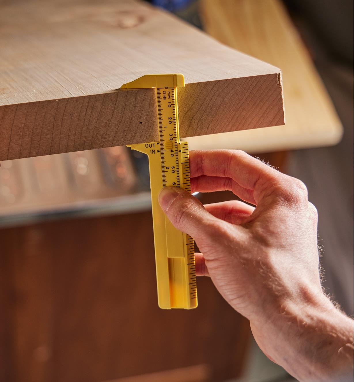 Using a pocket caliper to measure the thickness of a plank of wood