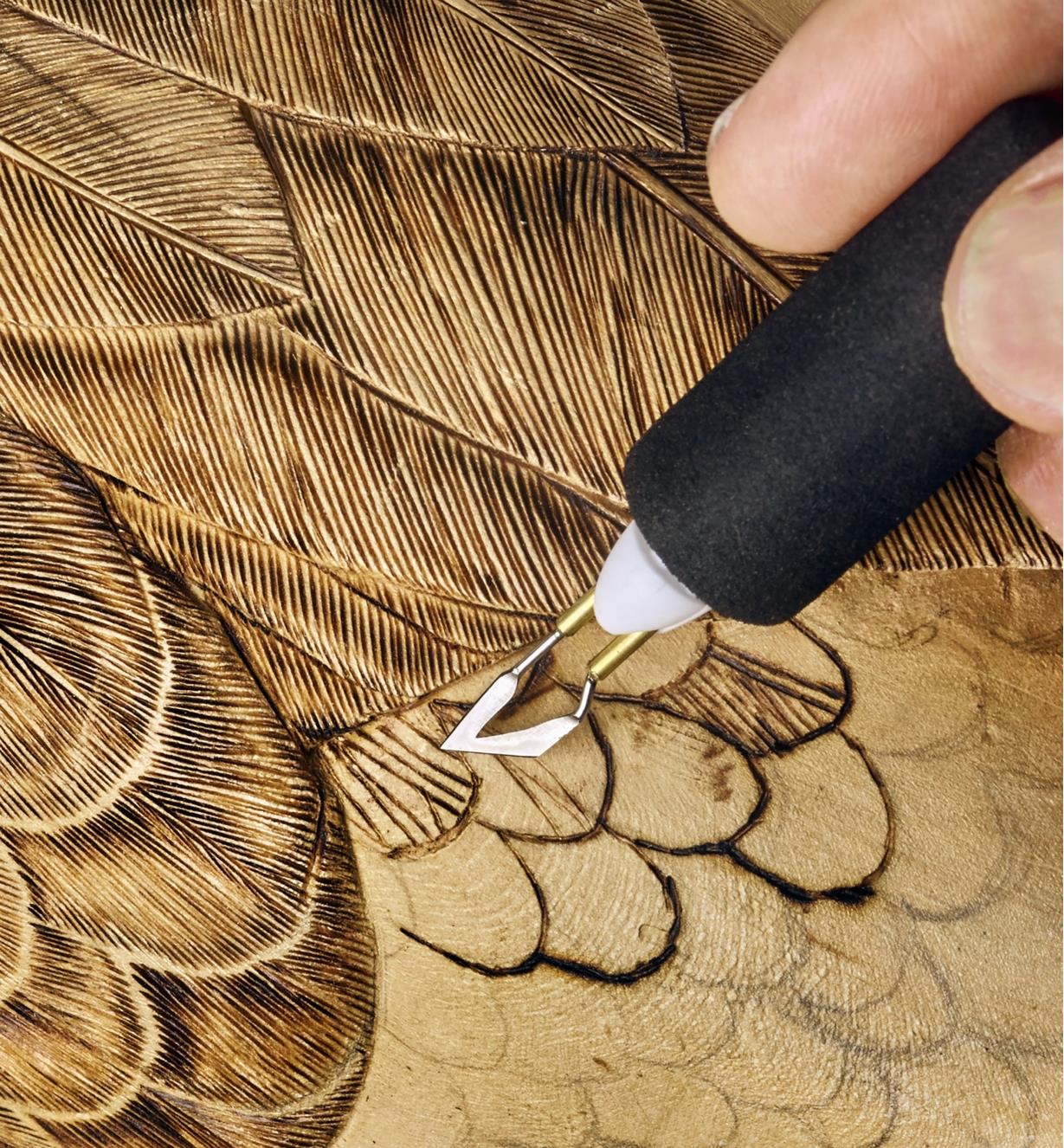 A woodworker uses the Razertip SK wood burning set to apply feather details to a bird carving