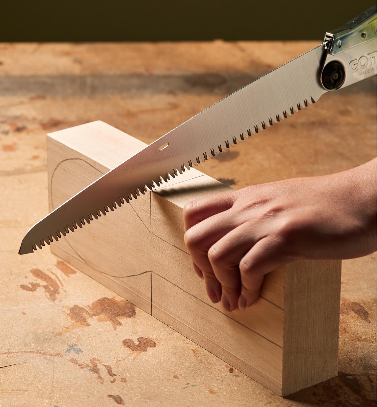 Preparing to make a cut in a wooden block using a Silky Gomboy folding saw