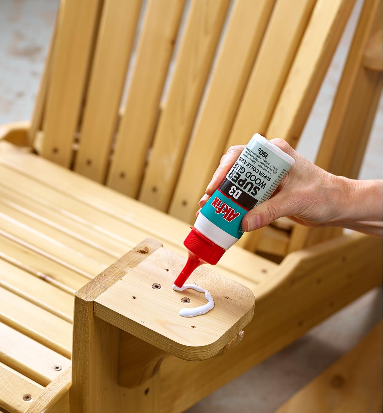 Applying glue to the arm of a wooden chair