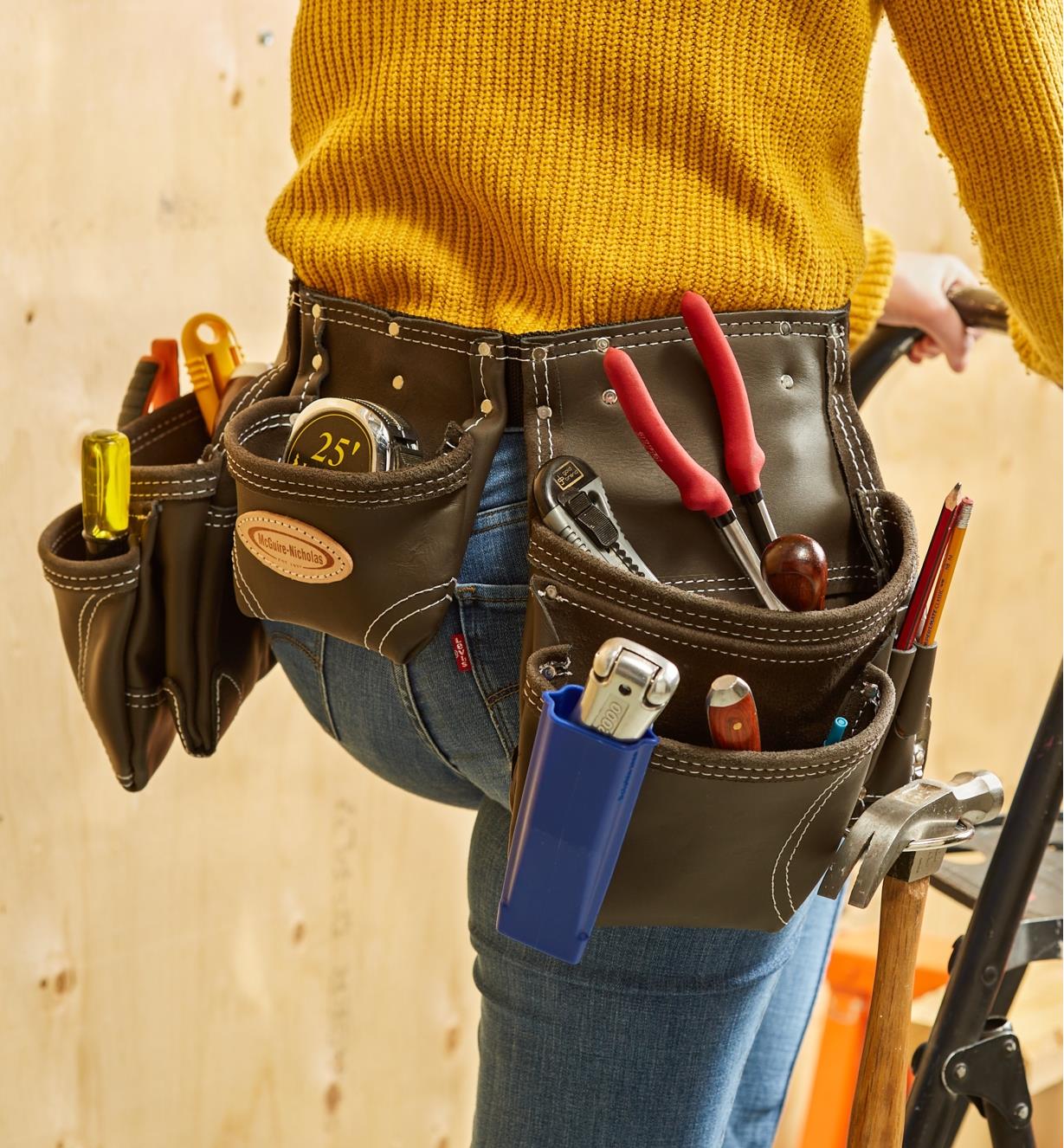 A person wearing a McGuire-Nicholas standard carpenter’s apron filled with tools