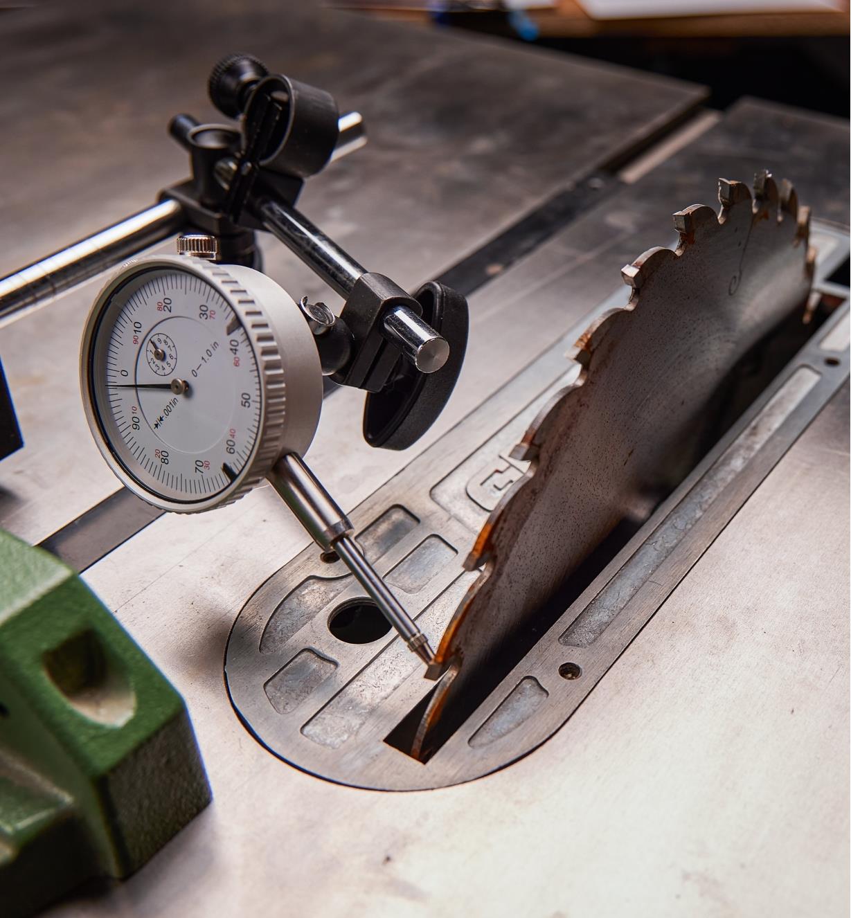 A dial indicator on a magnetic base being used to check a blade on a table saw