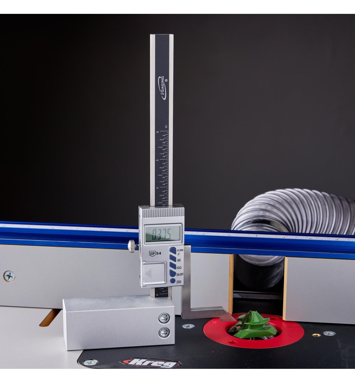 A digital height gauge sits on a router table and measures the height of a router bit