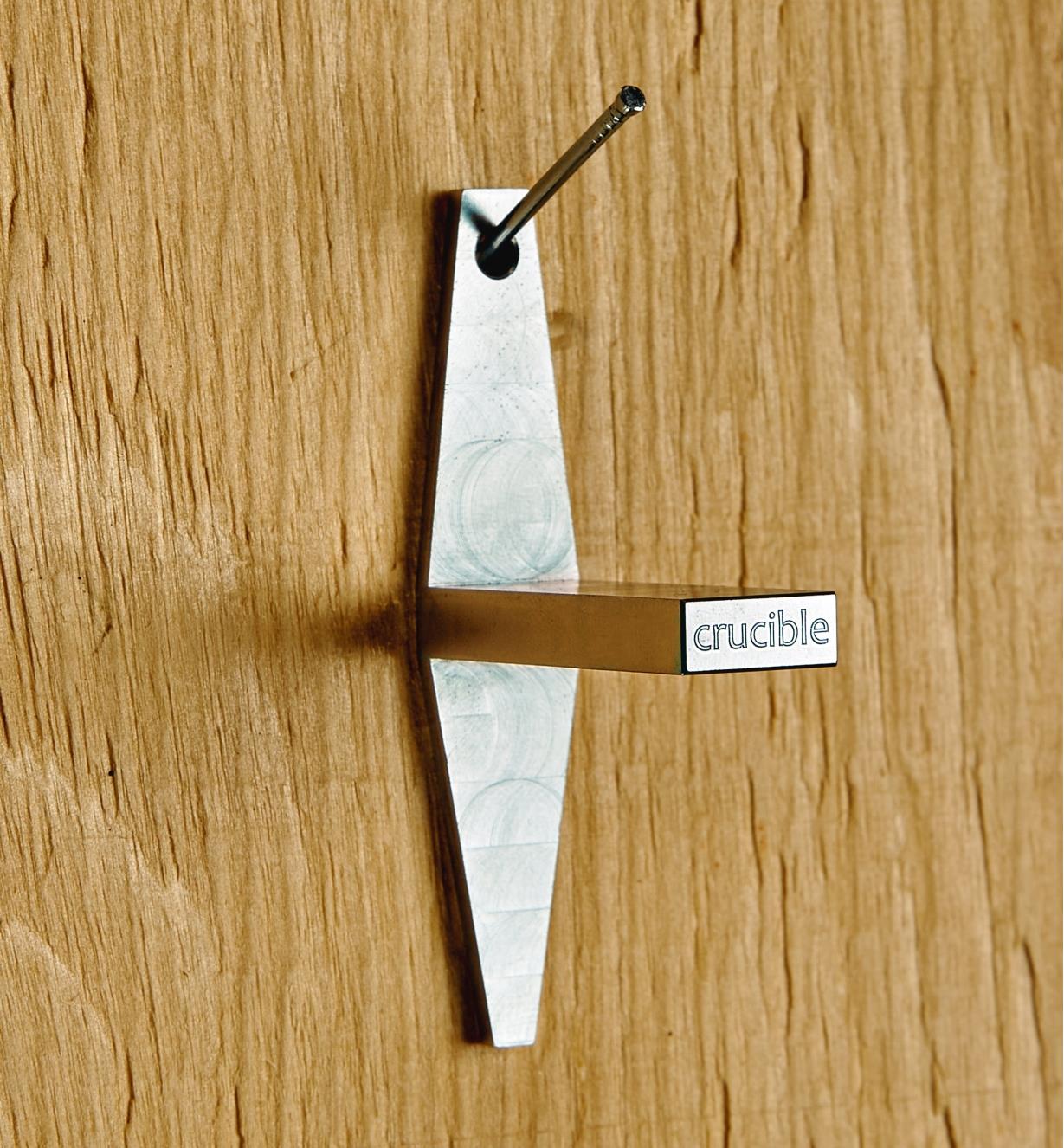 A dovetail template hangs on a nail on a wall