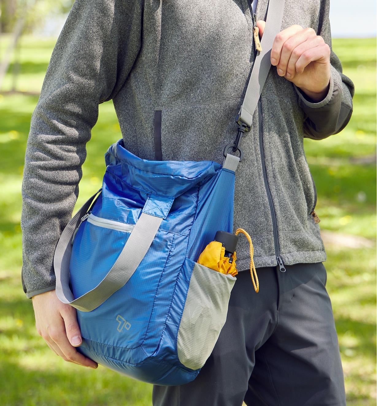 A packable shoulder bag being worn over someone’s shoulder