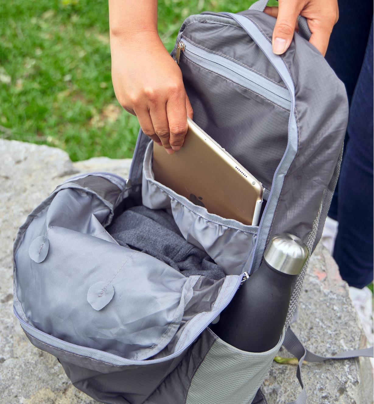 A notebook being removed from an open packable backpack
