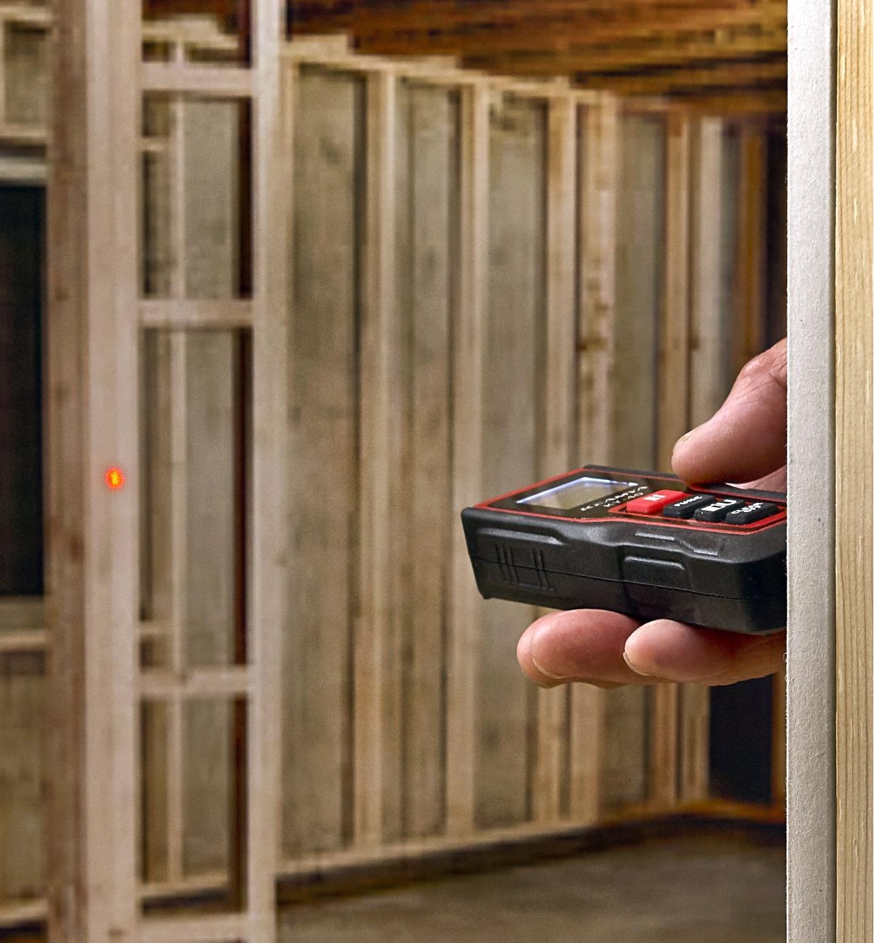 A pocket laser measure is being used to measure the distance between two walls