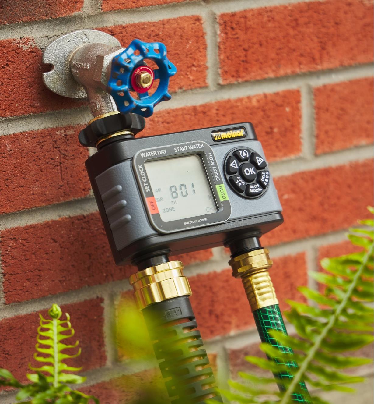 A two-zone electronic water timer connected to two hoses and an outdoor water faucet