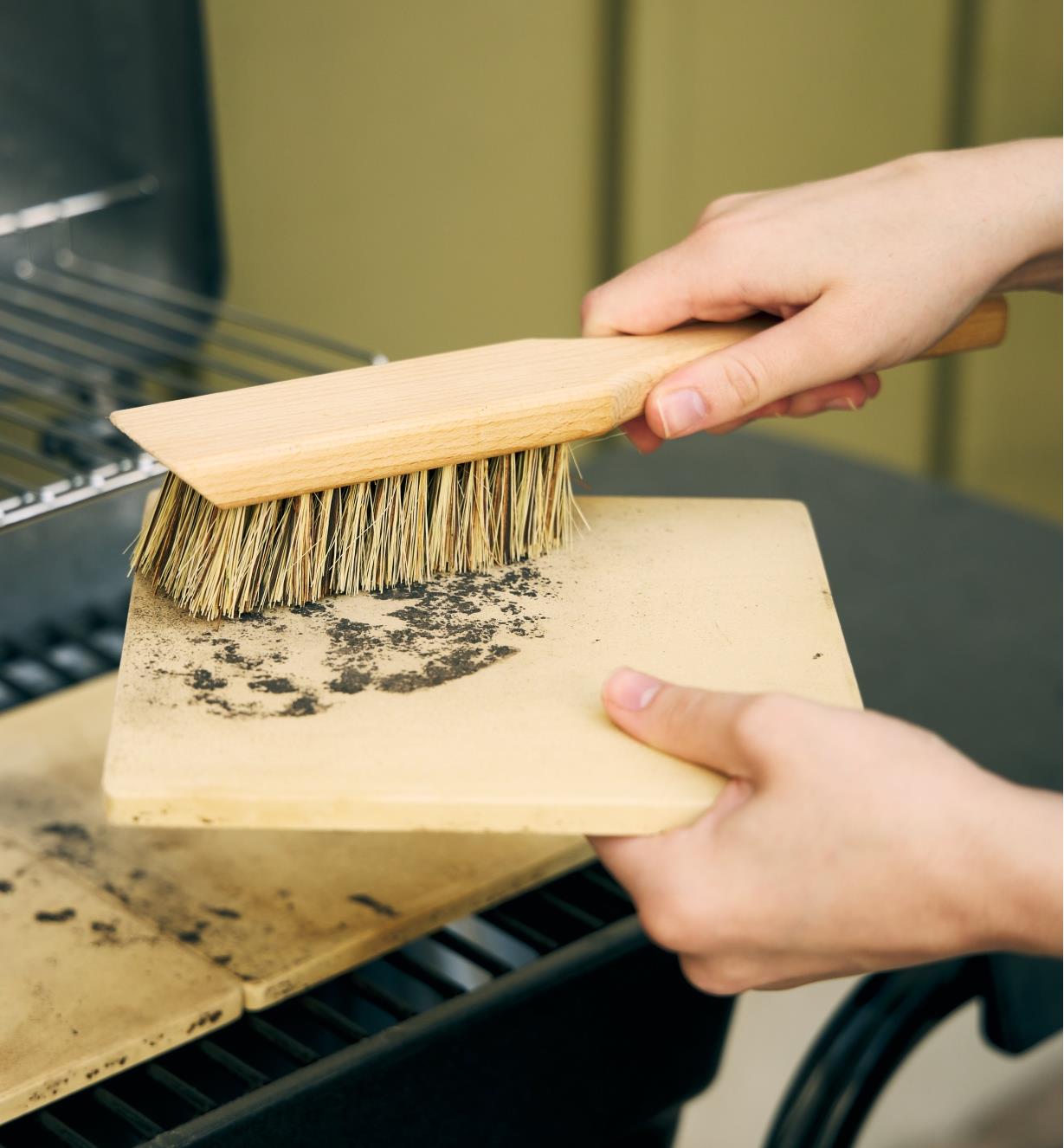 Using the toolshed brush to clean a barbecue pizza stone