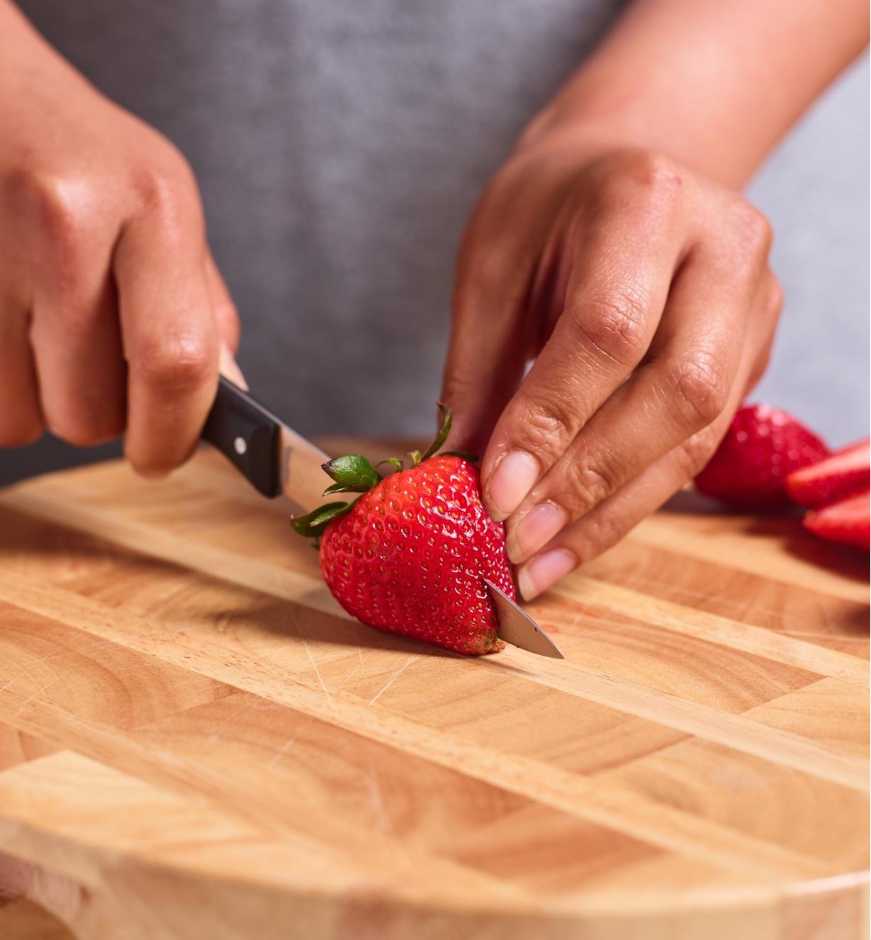 Personne coupant une fraise avec un couteau à légumes à dents ultra-fines