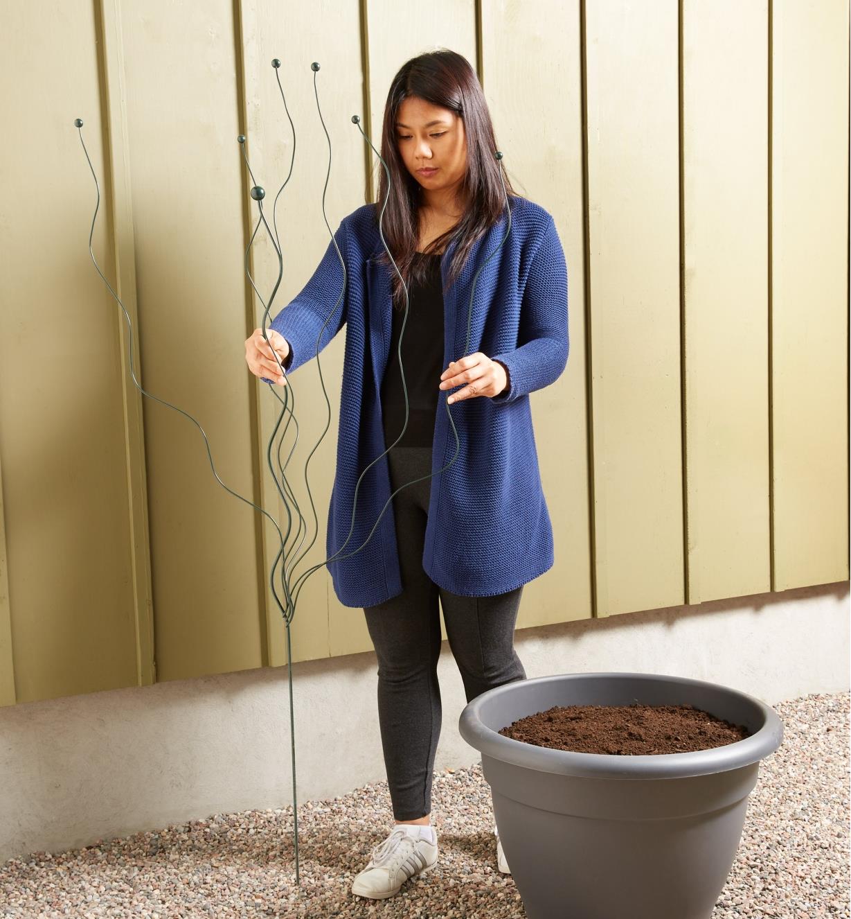 A woman holds the flexible garden stake upright to show scale