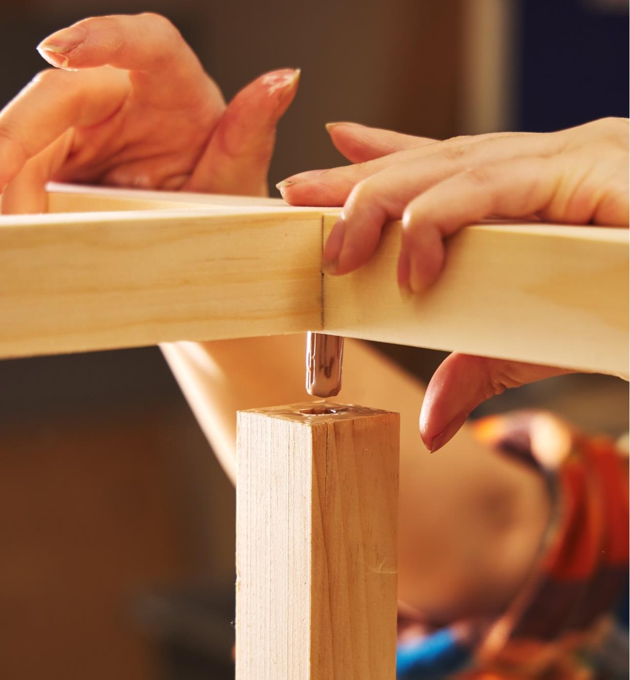 Attaching the jointed arms of the hook and ring game to the post with a dowel