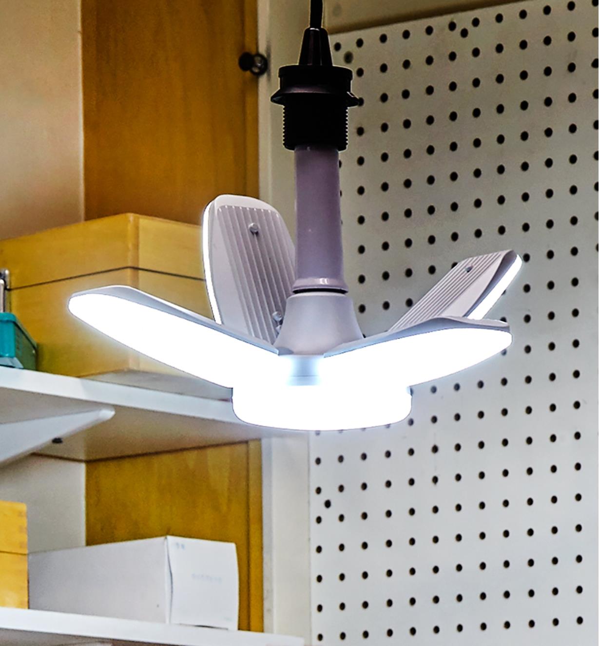 A directional LED ceiling light in a workshop, with two arms tilted up to illuminate the walls