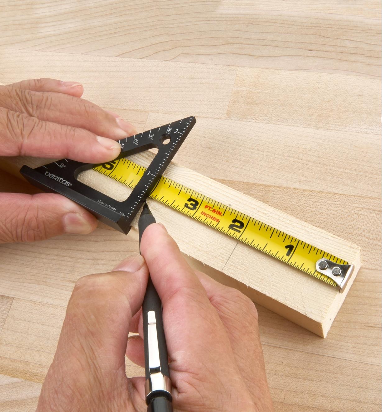 Personne utilisant une équerre de traçage à chapeau de 2 1/2 po posée sur un ruban à mesurer pour tracer une ligne sur une pièce de bois