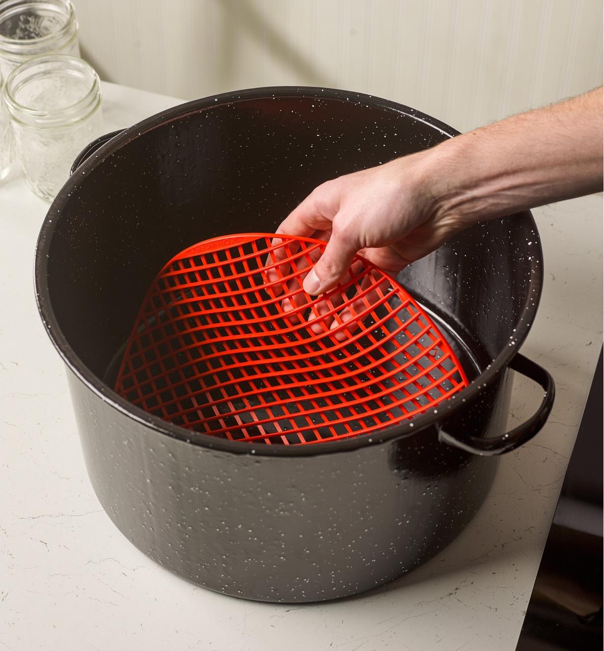 Placing a silicone canning mat into the bottom of a large pot