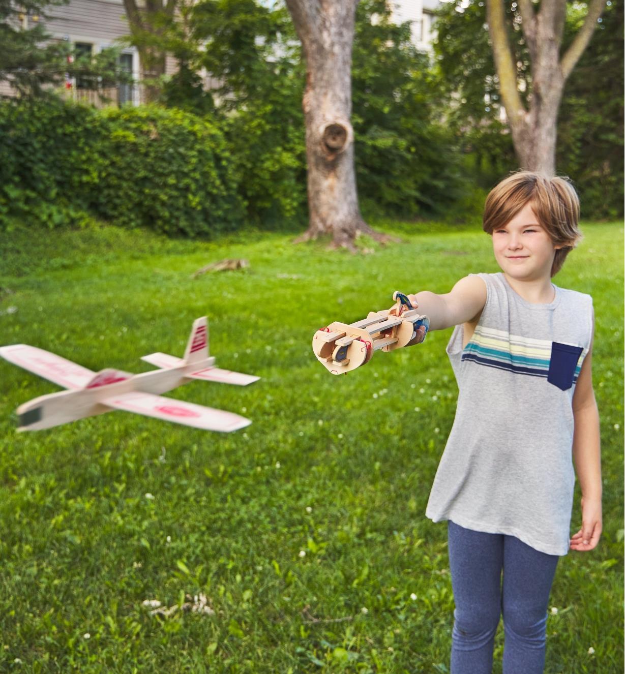 Enfant lançant un planeur en balsa prêt-à-monter avec une catapulte pour planeur en papier
