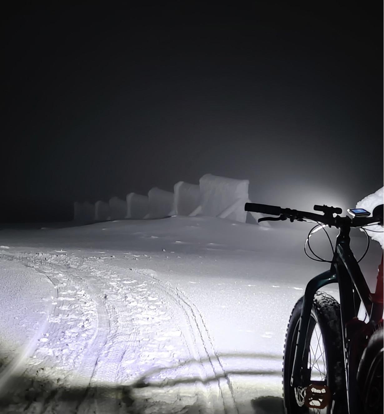 Lampe Suprabeam M6xr fixée au guidon d'un vélo et éclairant un chemin enneigé de nuit