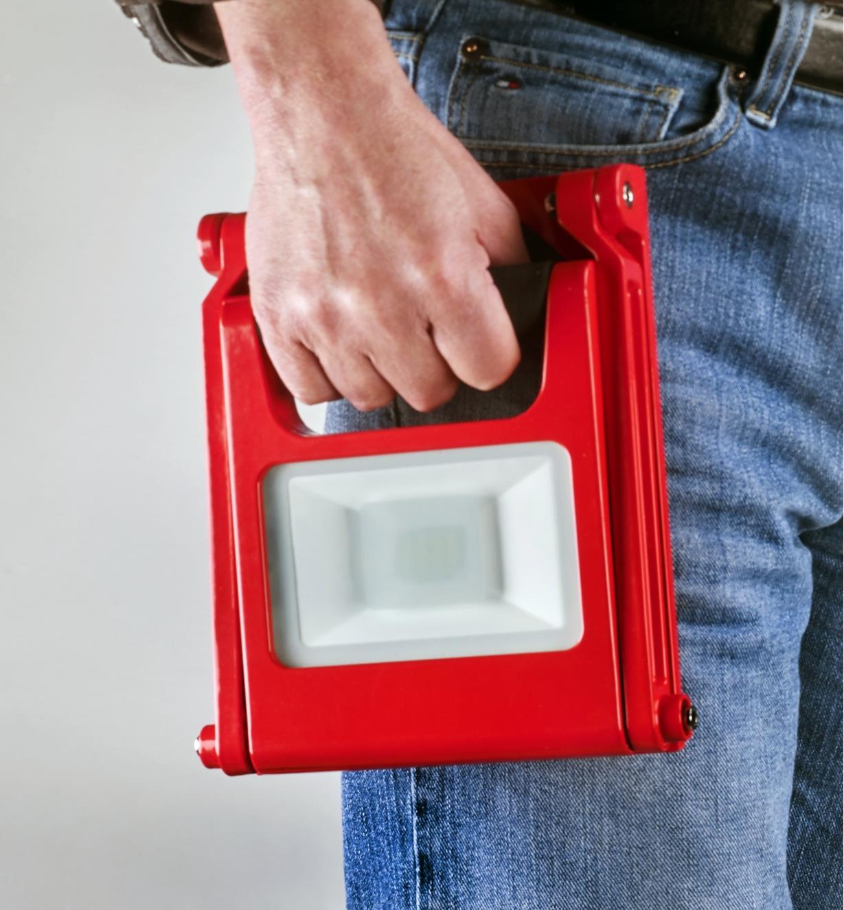 Carrying a rechargeable LED floodlight folded up for portability