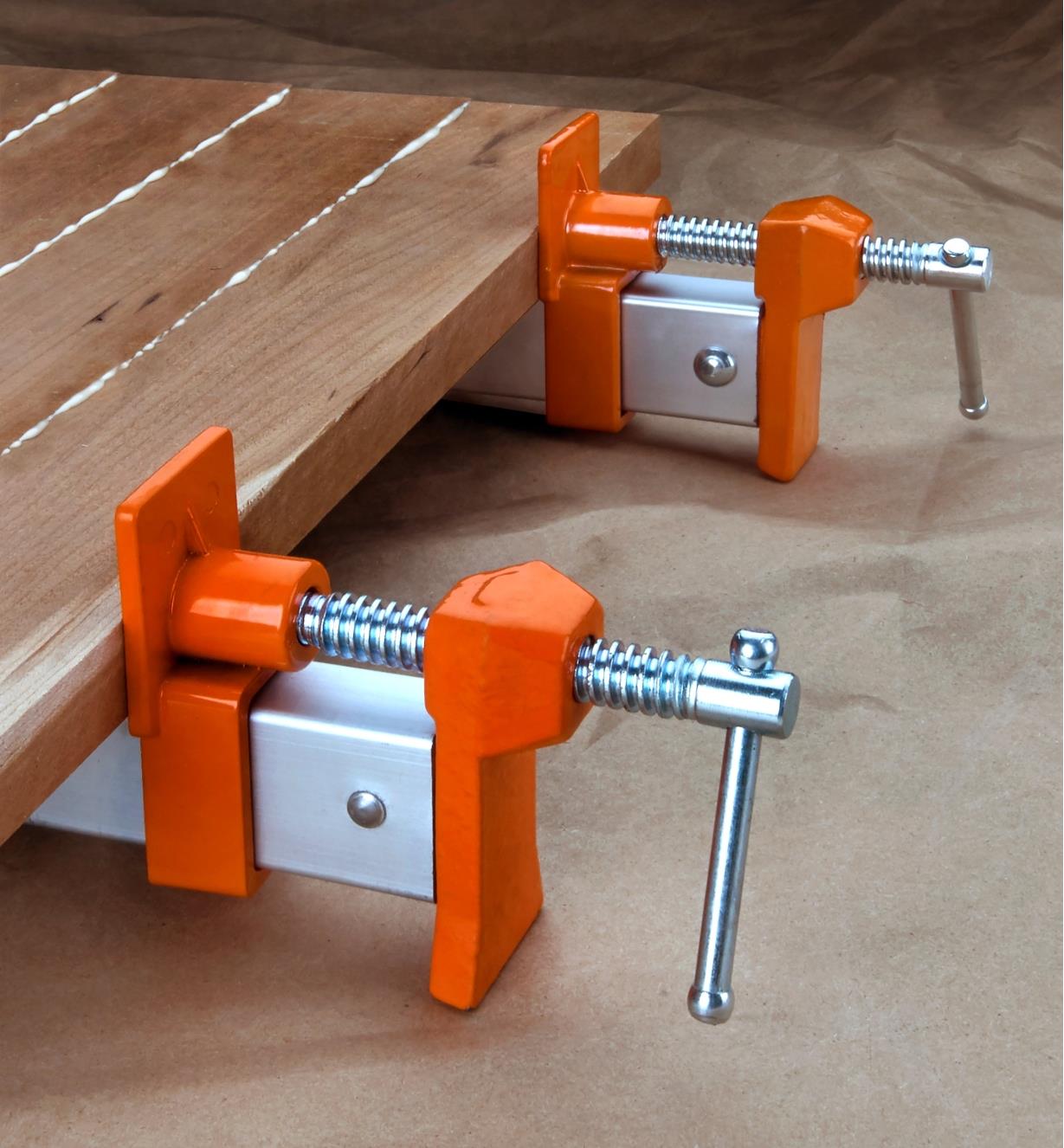 Two Jorgensen aluminum bar clamps holding a panel glue-up together while the glue sets