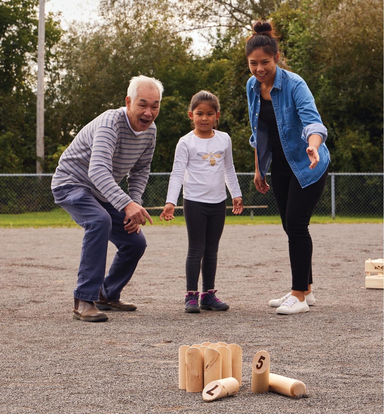 A man, a woman and a girl playing Mölkky outdoors