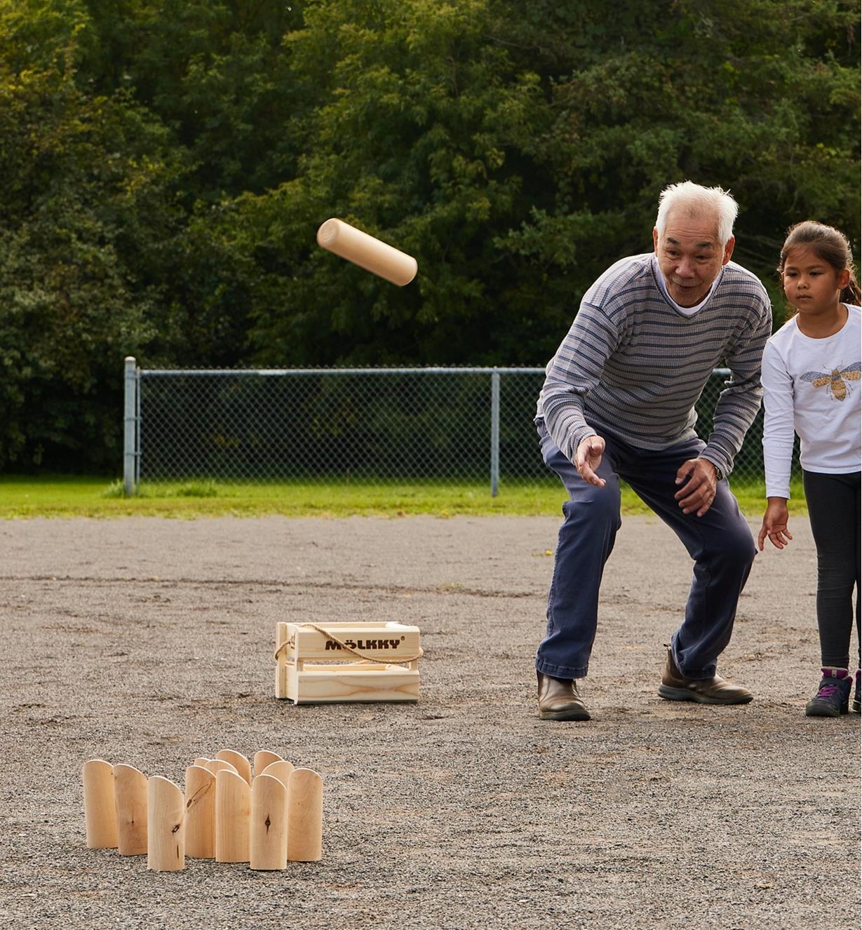 A man and a girl playing Mölkky outdoors