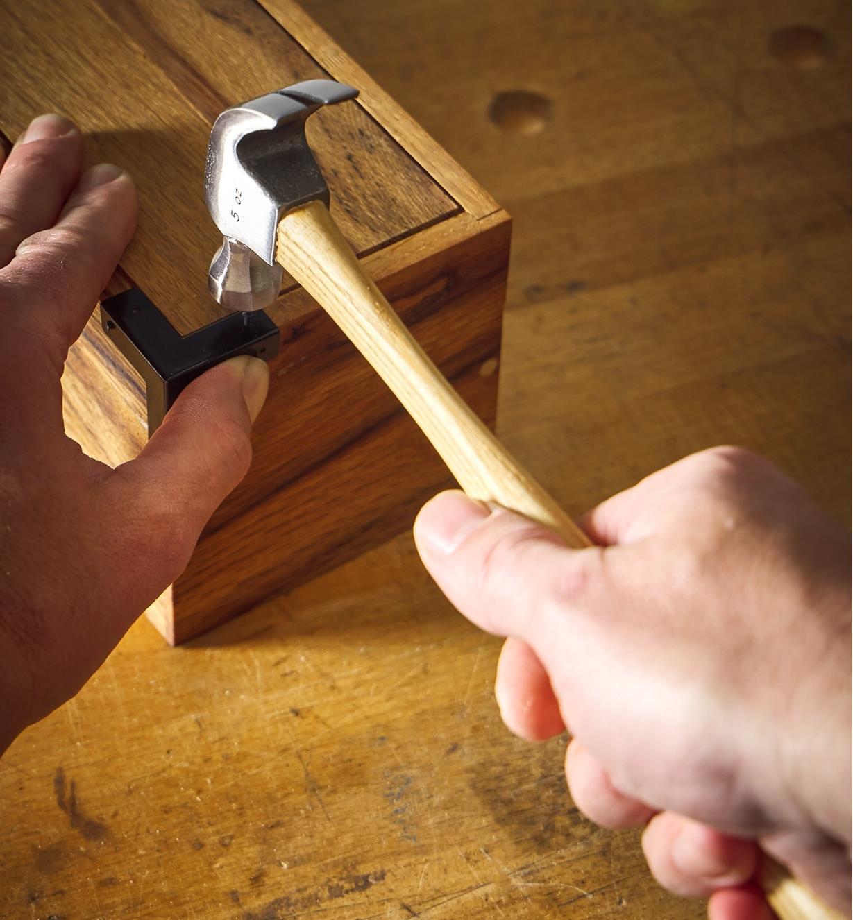 Using a 5 oz hammer to drive a small nail into a wooden box