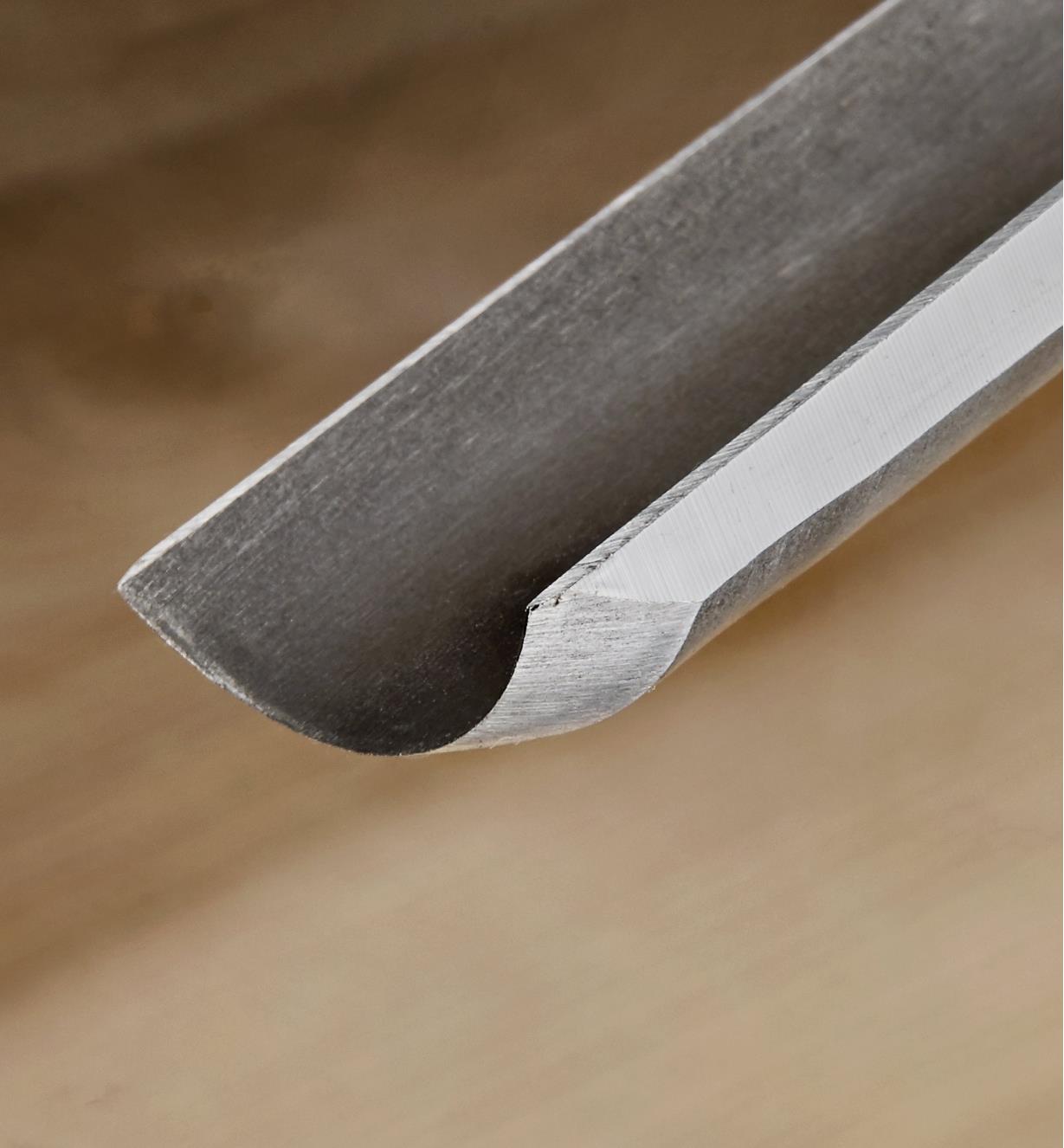 A close-up view of the tip of a Narex firmer gouge showing the curved blade shape