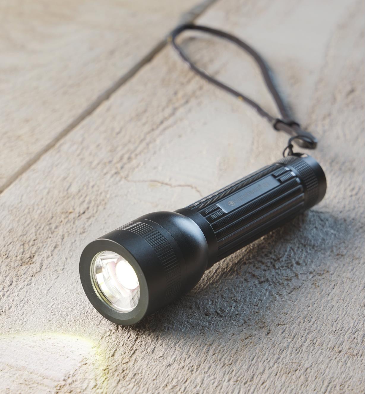 A flashlight lying on a board