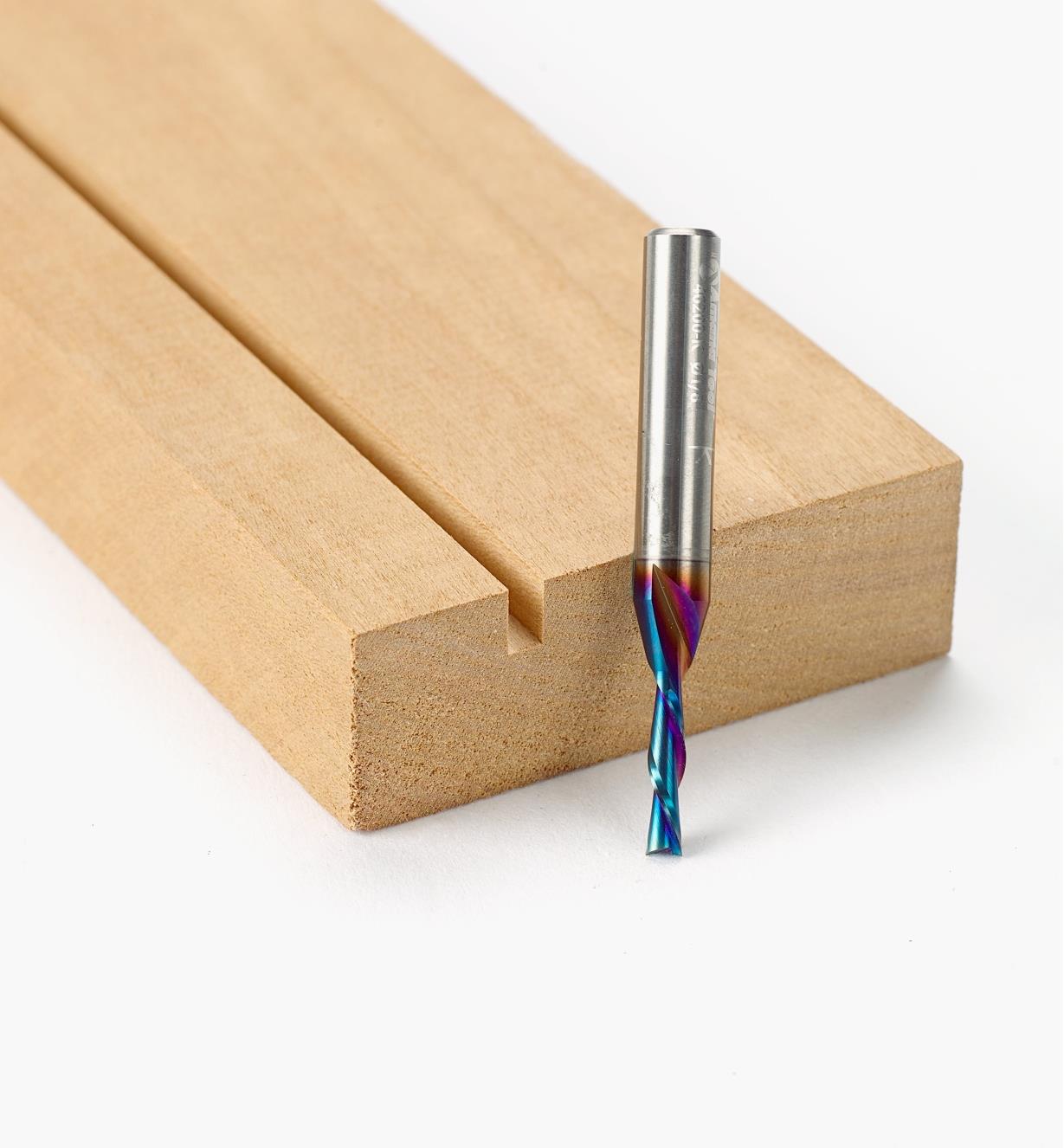 A 1/8 inch diameter downcut bit next to a board with a narrow groove cut into it