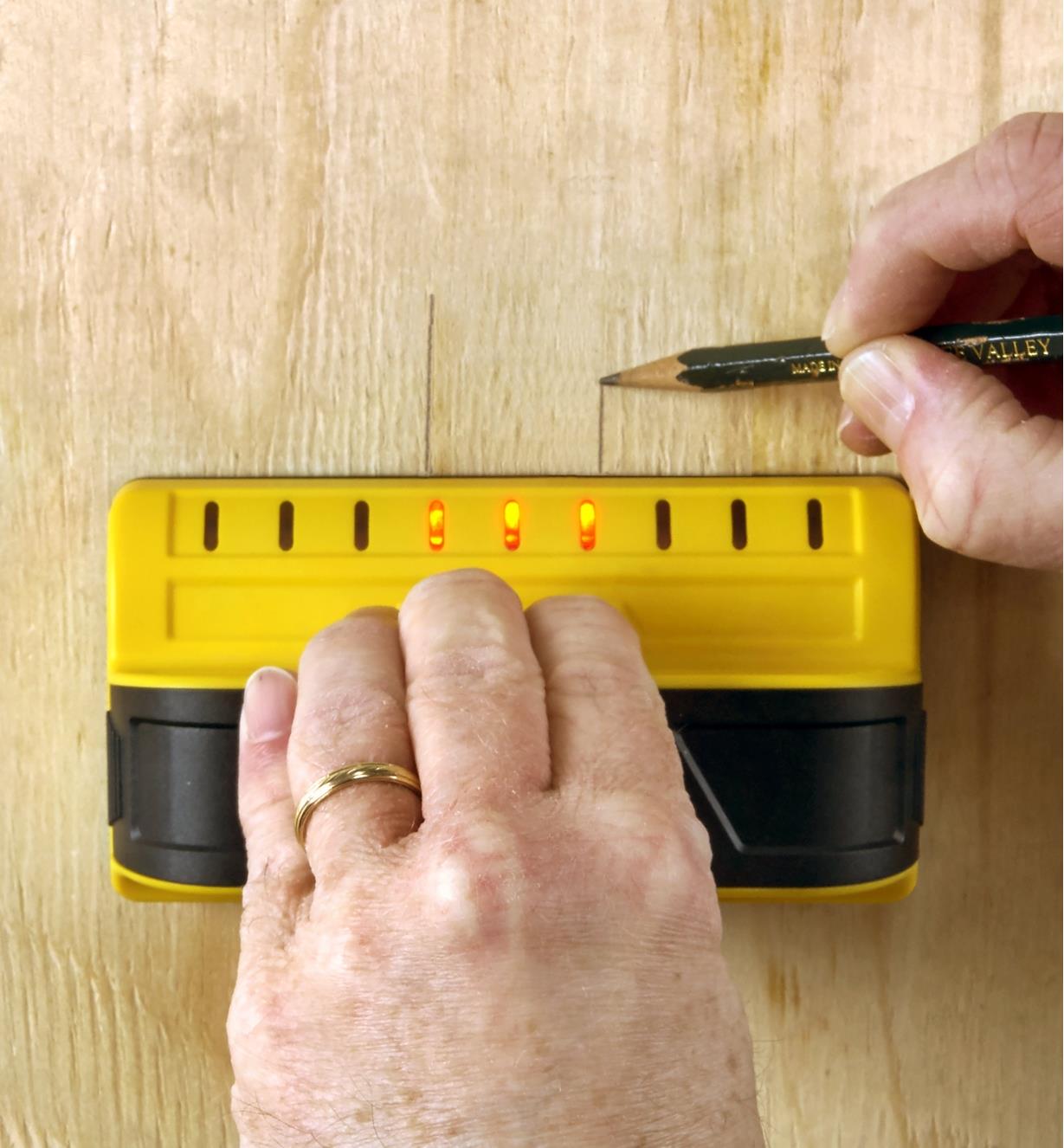 Using a Franklin M90 stud detector to mark the outlines of an obstruction behind a wooden panel