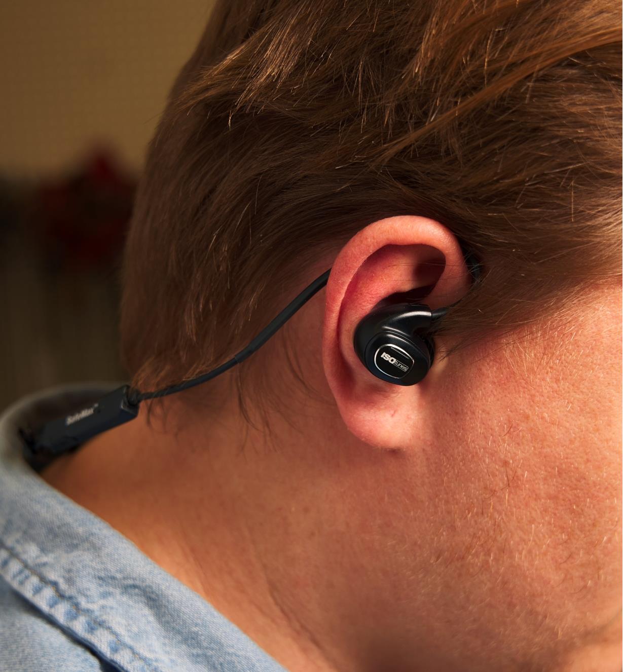 ISOtunes earbud hearing protectors worn with the pliable wire formed behind the ear for a snug fit