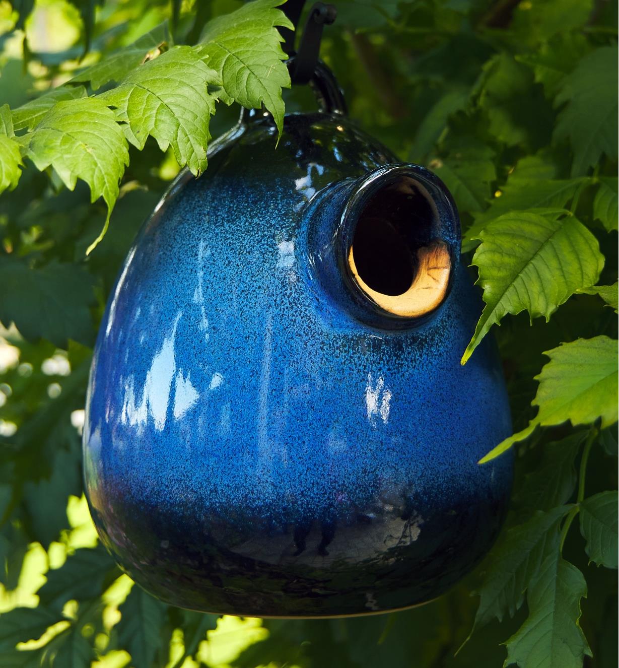 The ceramic bird home hanging in a tree