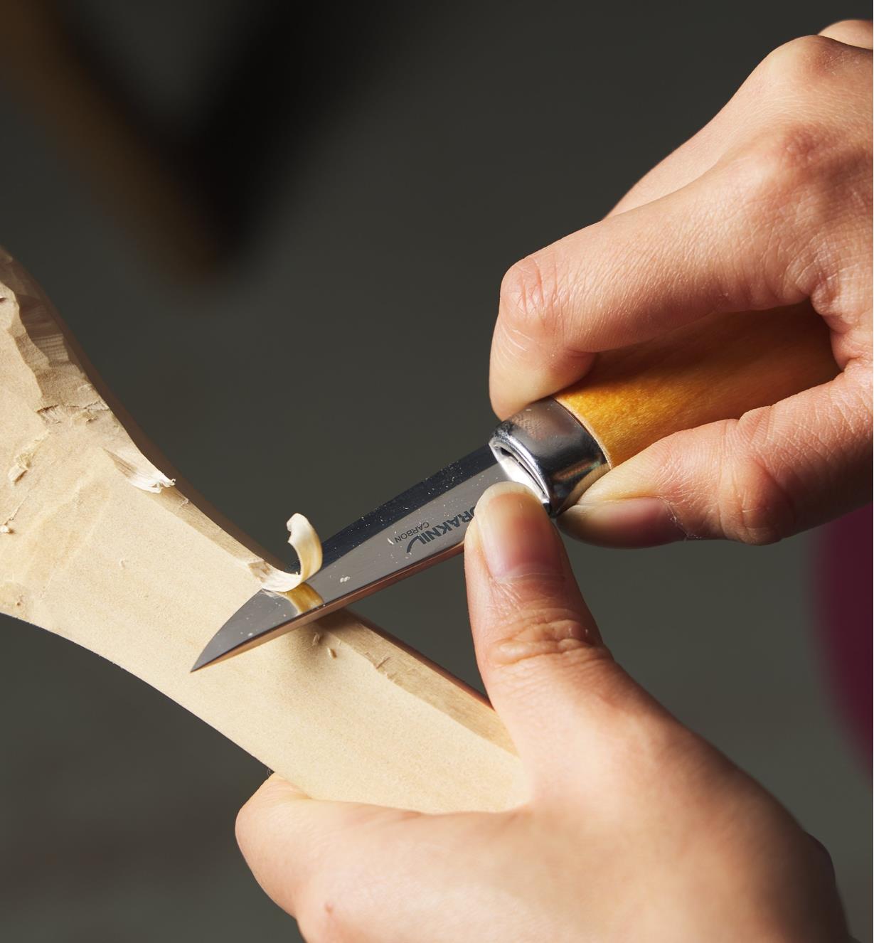 Personne sculptant une cuillère en bois avec un couteau Slöjd 
