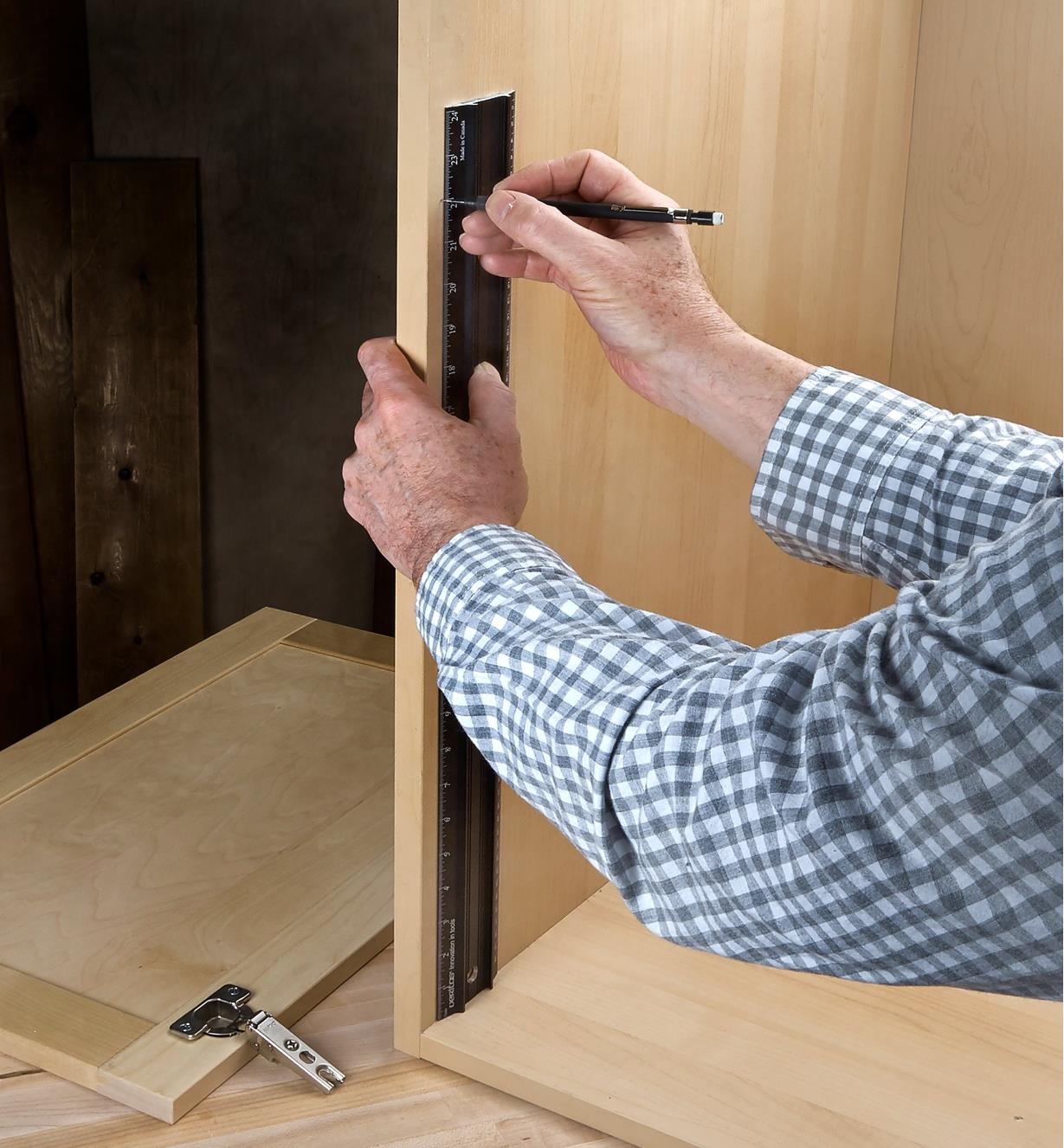 Standing a shop rule on end to lay out hinge locations on an inside wall of a cabinet