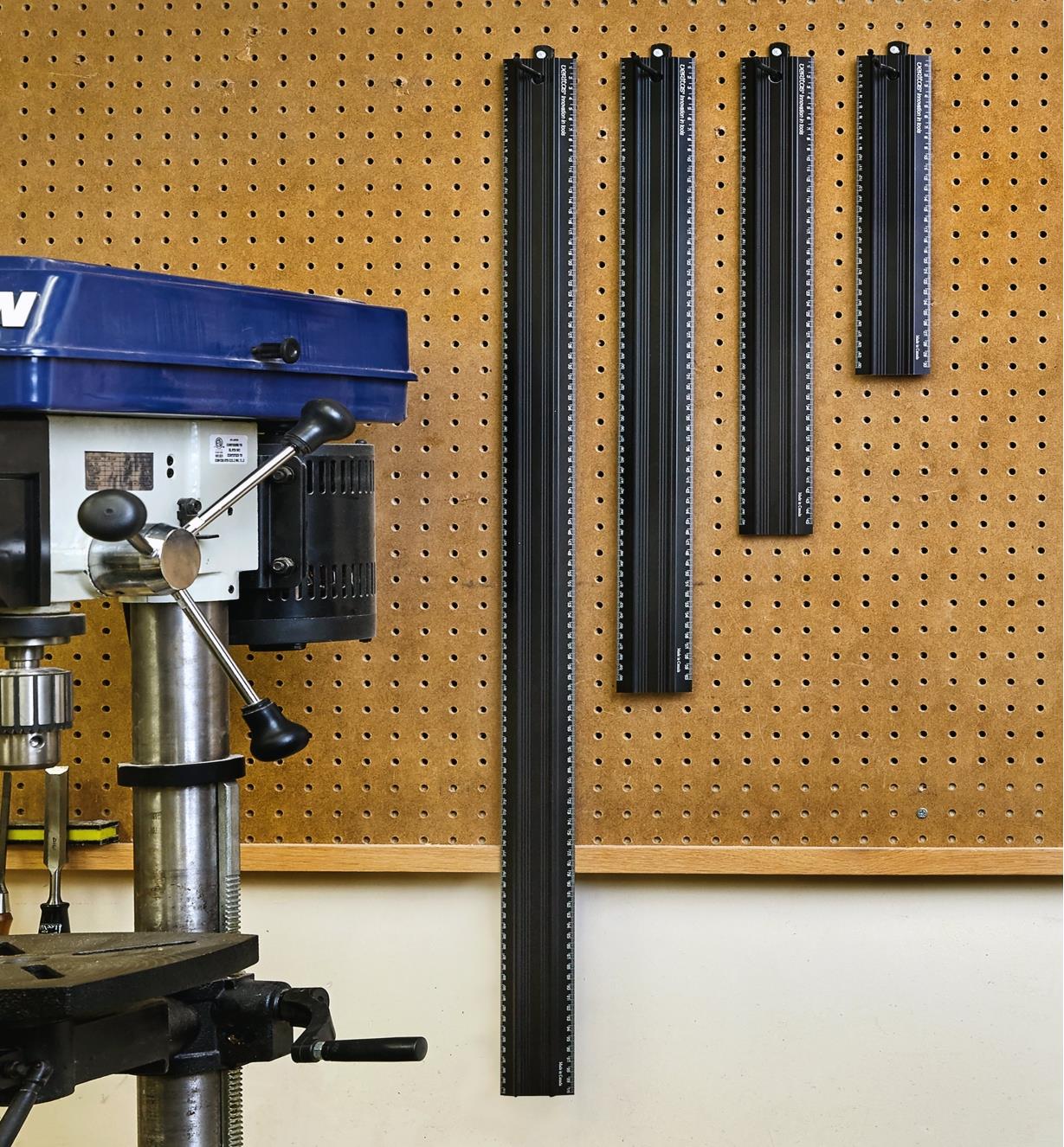 Four sizes of Veritas metric shop rules hung on a pegboard near a drill press