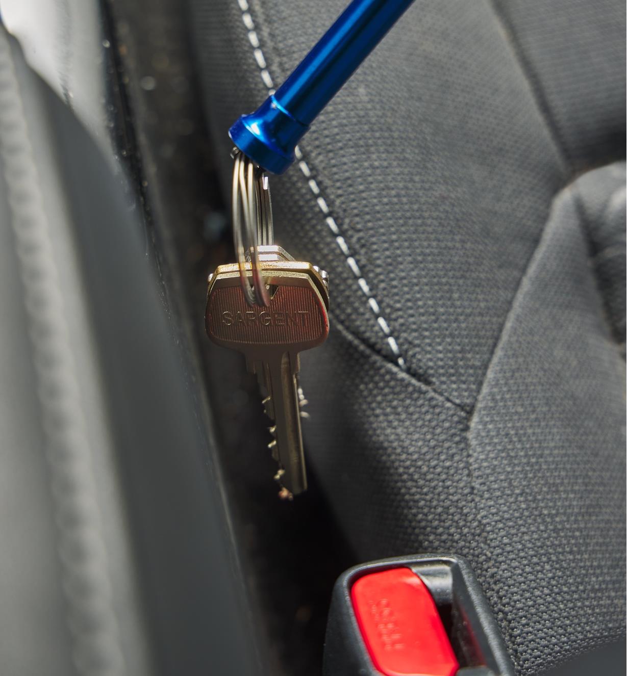Récupérer des clés dans la fente à côté d'un siège d'auto à l'aide d'un agrippeur magnétique