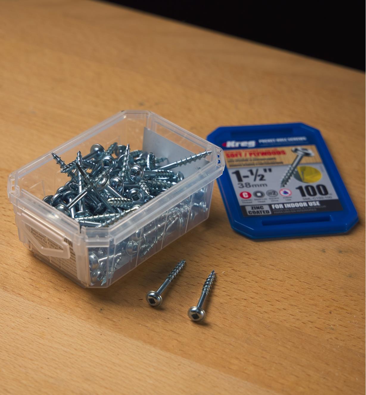 Two pocket-hole screws in front of a container full of screws
