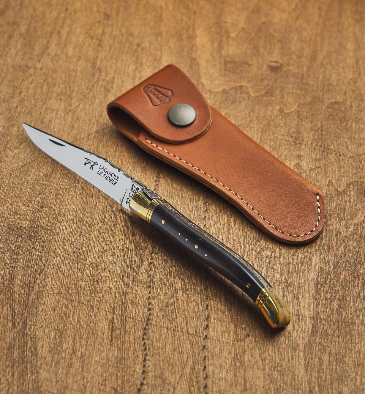 An open laguiole knife next to a leather case