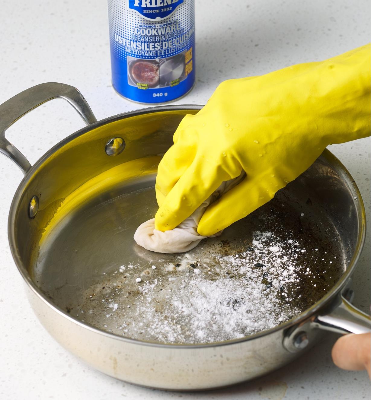 Using a damp cloth and Bar Keepers Friend to clean a pan’s cooking surface 