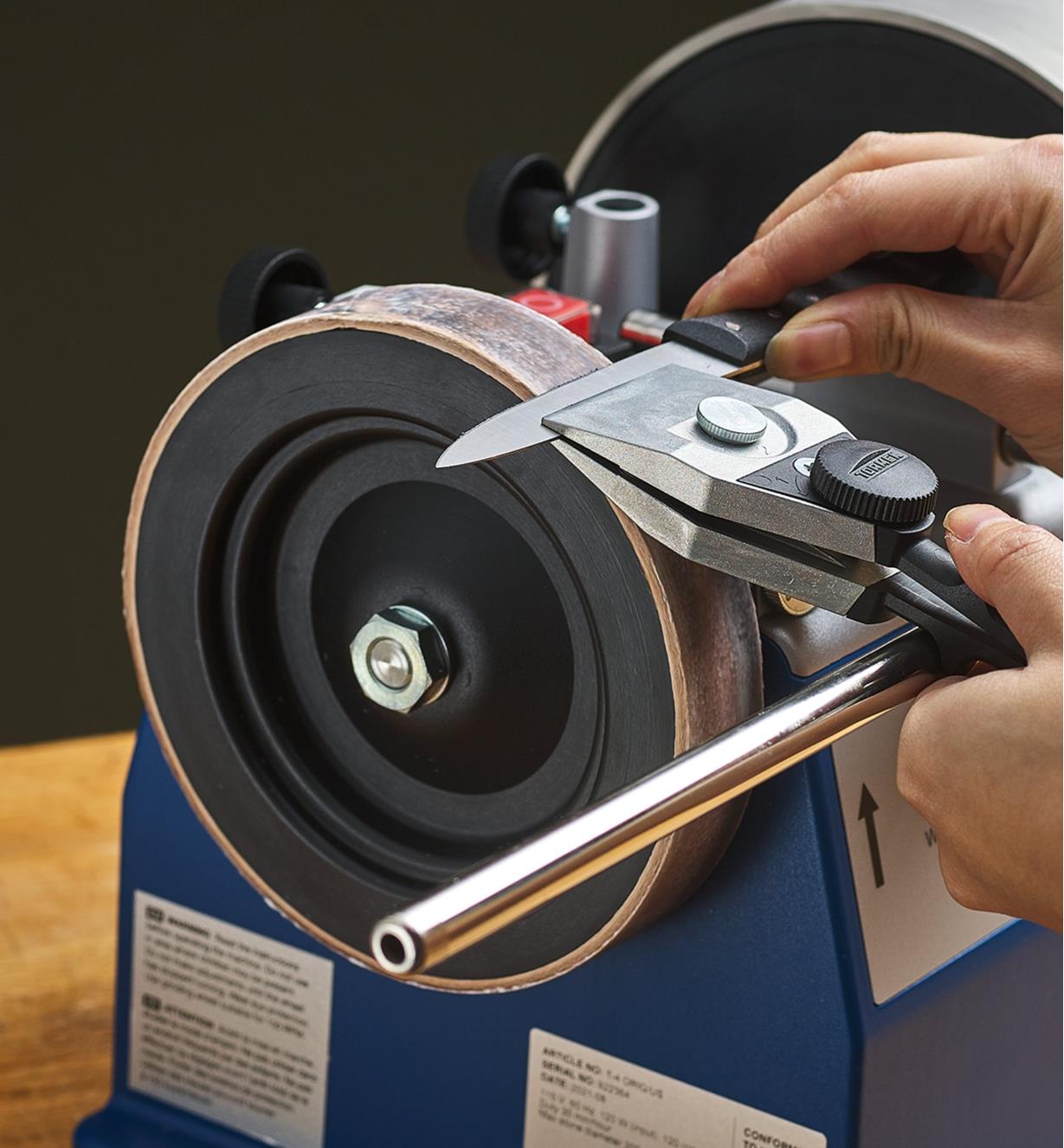 A centering knife jig holds a knife being honed on a leather wheel 