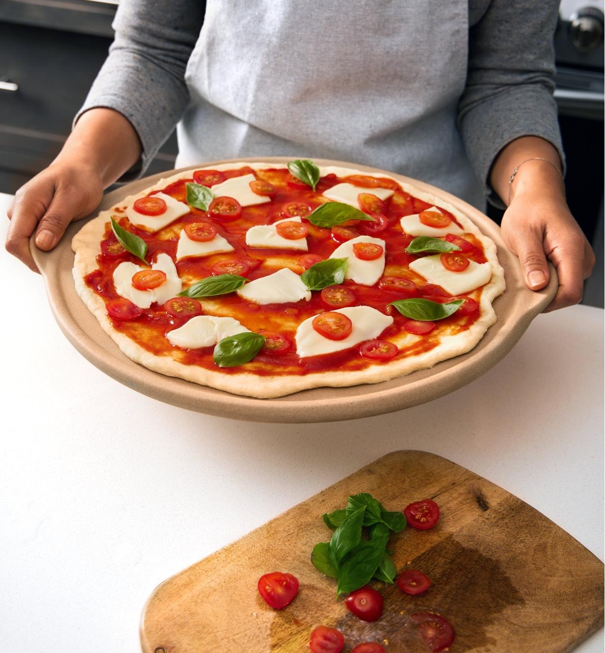 Pizza non cuite garnie de sauce tomate, de bocconcini, de tomates cerises et de feuilles de basilic