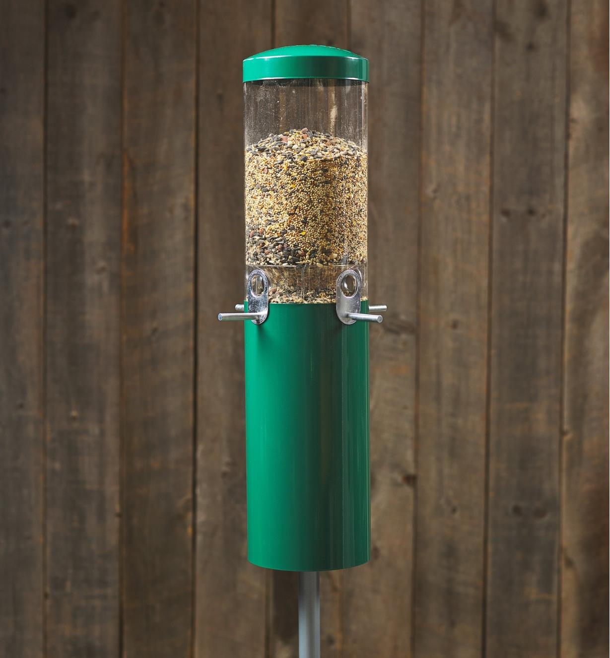 A pole-mounted squirrel-proof bird feeder installed and filled with bird seed