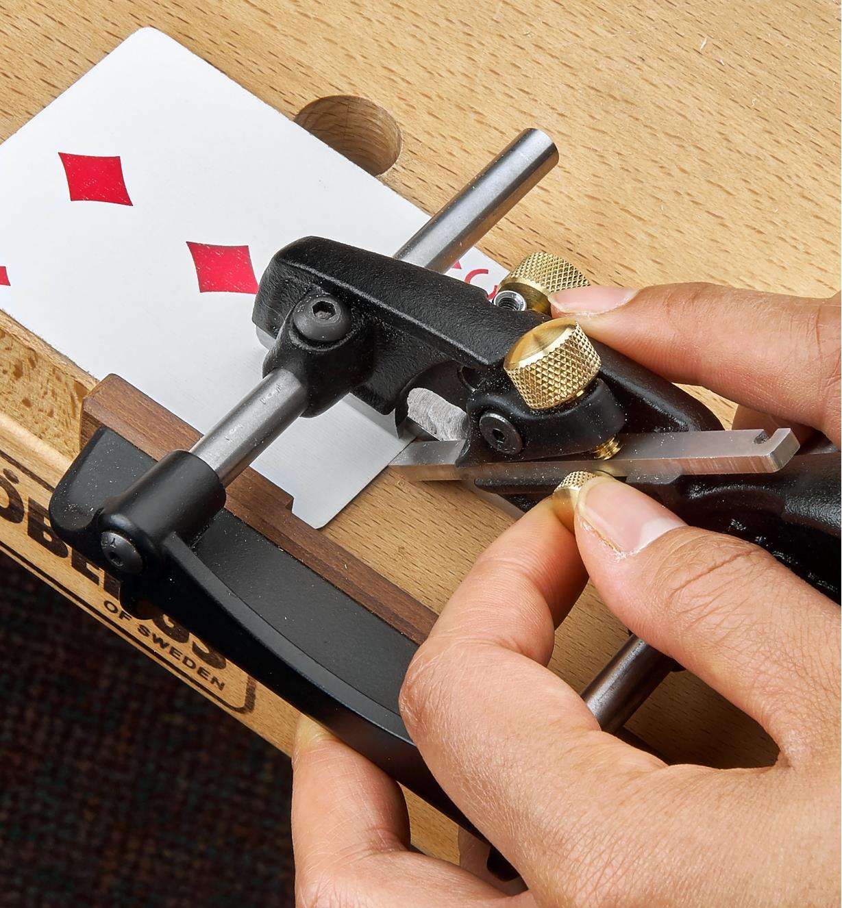 Setting blade projection on a box-maker’s plow plane, using a playing card as a shim under the skate