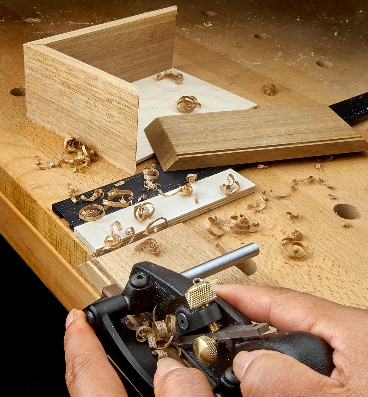 Using a box-maker’s plow plane to cut a groove in the wall of a wooden box to hold the box bottom