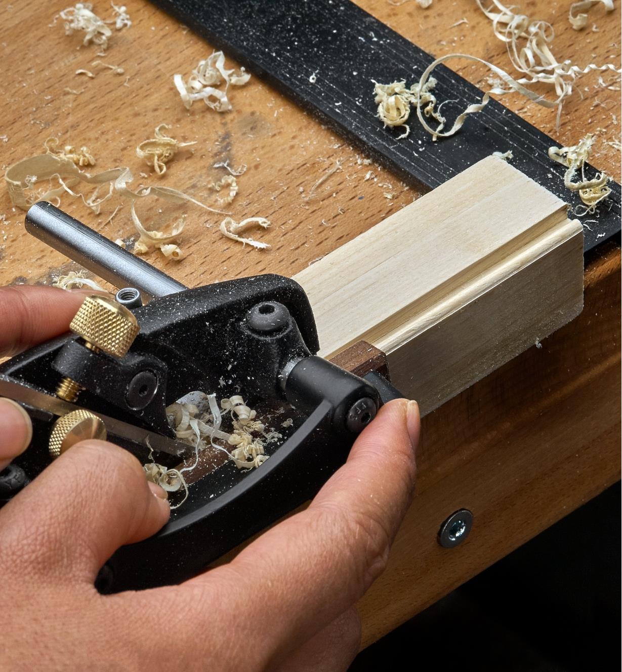A left-hand box-maker’s plow plane being used to cut beading on the edge of a piece of wooden stock