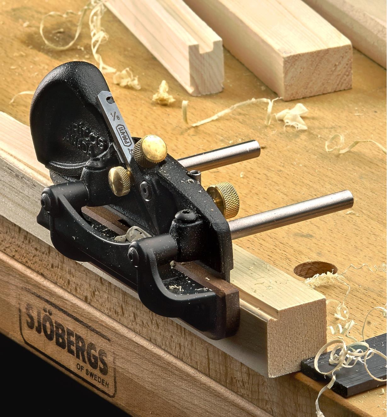 A left-hand box-maker’s plow plane being used to cut beading on the edge of a piece of wooden stock