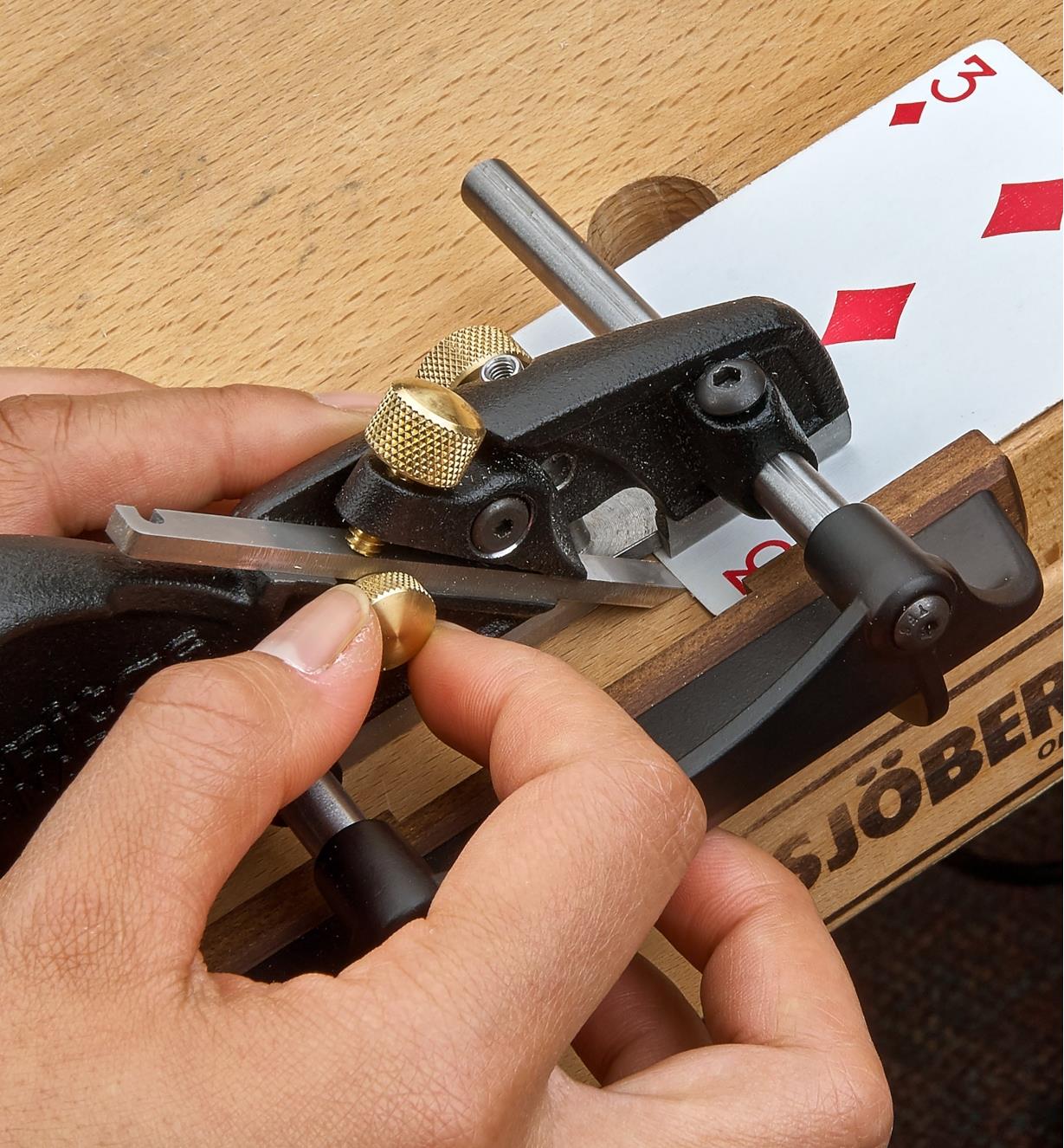 Setting blade projection on a box-maker’s plow plane, using a playing card as a shim under the skate